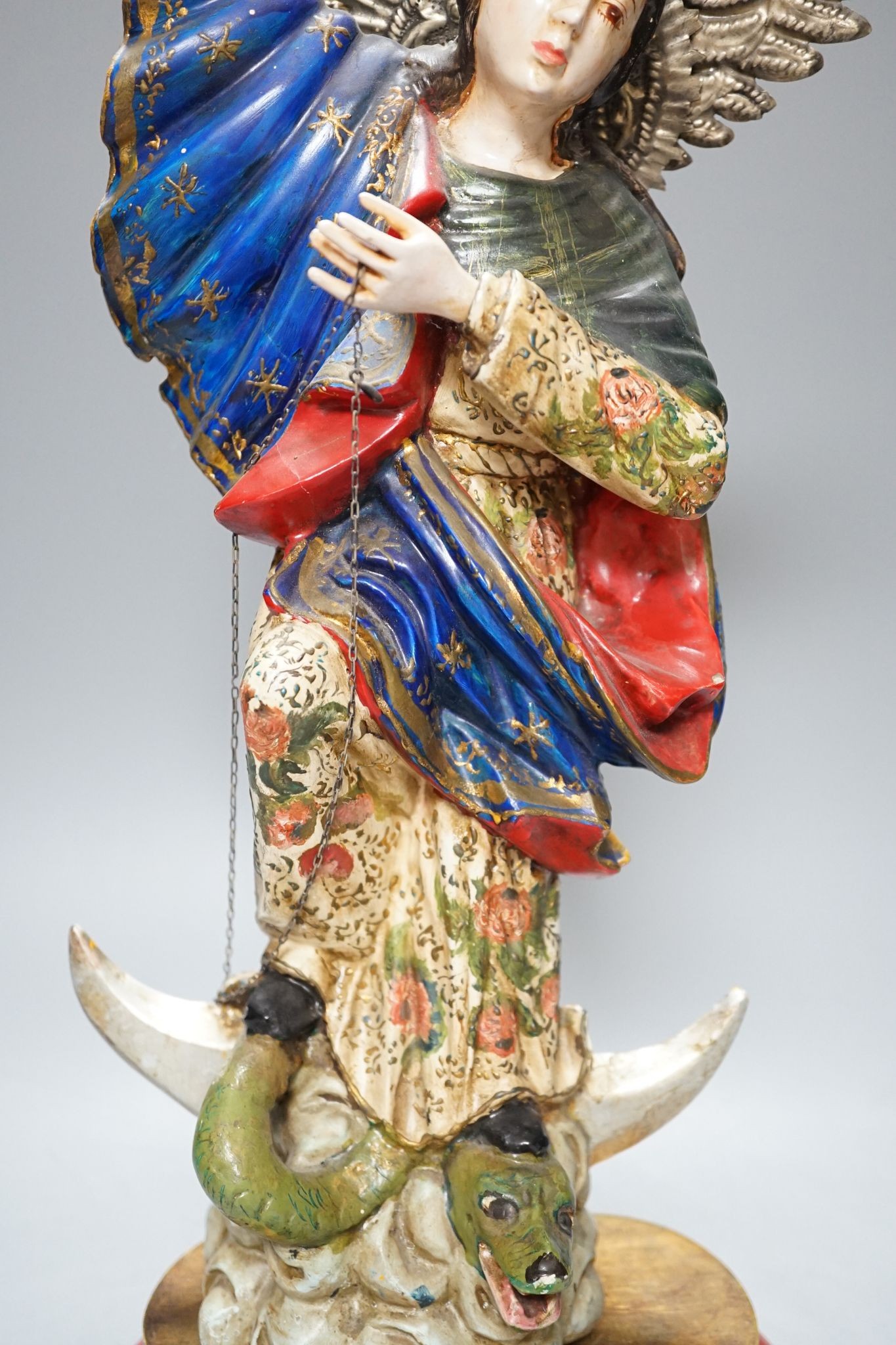 A painted South American angelic figure, standing on a dragon on a crescent moon 49cm